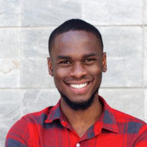 A smiling black man in a red shirt.