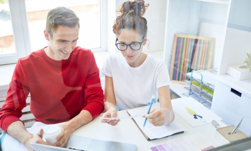 Two people sitting at a desk looking at a laptop.