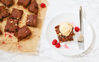 A plate of brownies with ice cream and raspberries.